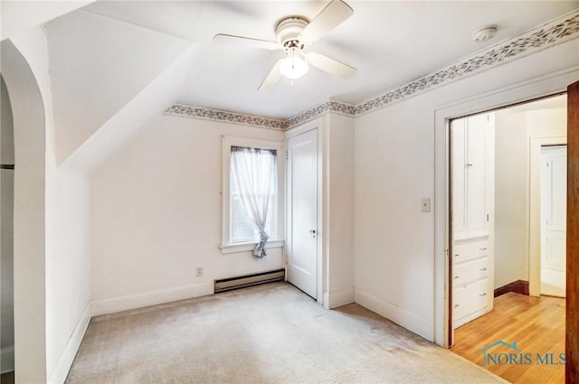 additional living space featuring arched walkways, light colored carpet, a baseboard heating unit, a ceiling fan, and baseboards