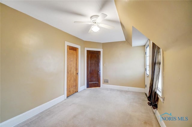 spare room featuring light carpet, ceiling fan, visible vents, and baseboards