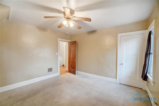 unfurnished room featuring light carpet, visible vents, a ceiling fan, and baseboards