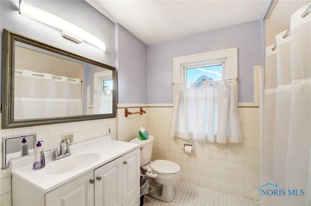 bathroom with toilet, tile patterned floors, curtained shower, vanity, and tile walls