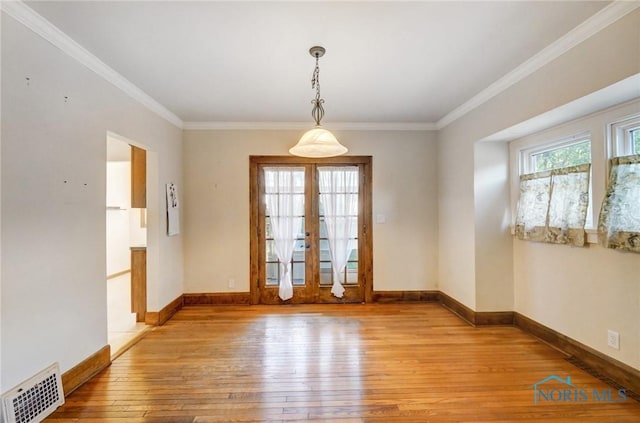 empty room with a wealth of natural light, visible vents, crown molding, and light wood-style flooring