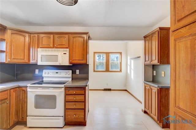 kitchen featuring light floors, visible vents, brown cabinetry, white appliances, and baseboards