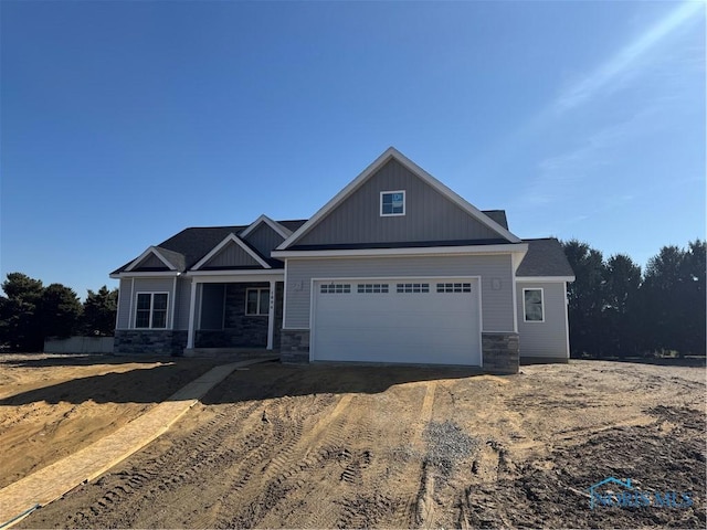 craftsman-style home featuring stone siding, a garage, driveway, and board and batten siding