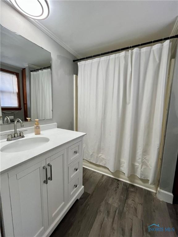 bathroom with shower / bath combination with curtain, crown molding, vanity, and wood finished floors