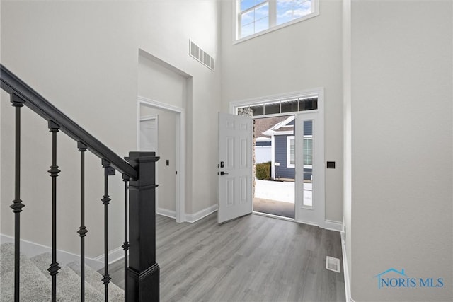 foyer entrance featuring a high ceiling, wood finished floors, visible vents, and baseboards