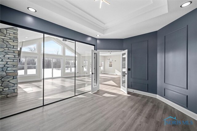 spare room with baseboards, a raised ceiling, and wood finished floors