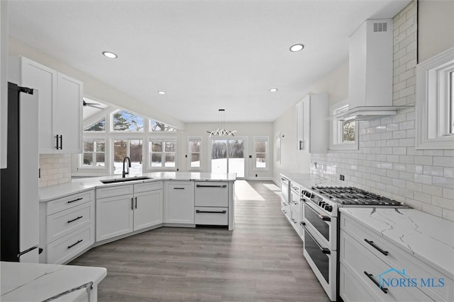 kitchen featuring white cabinets, double oven range, a sink, and wall chimney exhaust hood