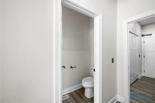 bathroom featuring baseboards, visible vents, toilet, and wood finished floors