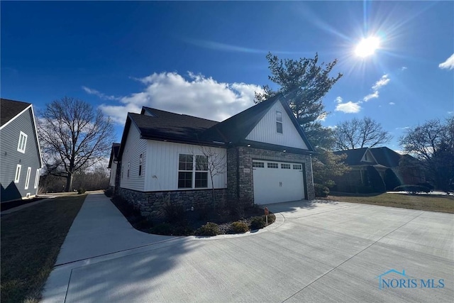 view of home's exterior featuring driveway, stone siding, and a garage