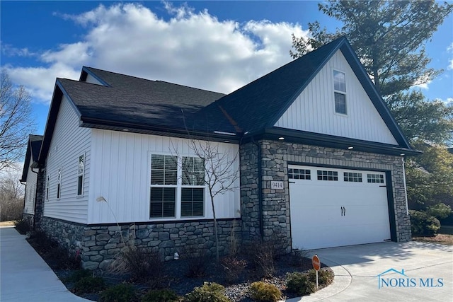 view of front of home with a garage, concrete driveway, roof with shingles, and stone siding