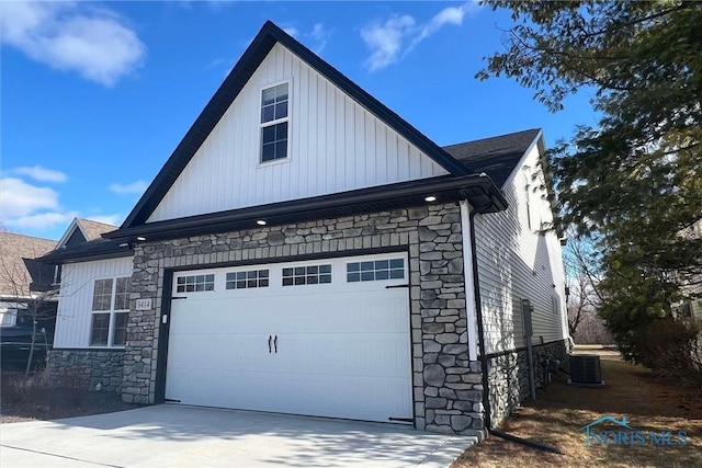 view of home's exterior with stone siding, central AC, and concrete driveway