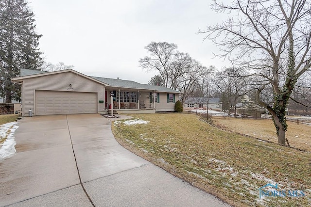 ranch-style home featuring an attached garage, covered porch, driveway, and a front lawn