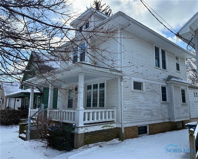 snow covered property with a porch