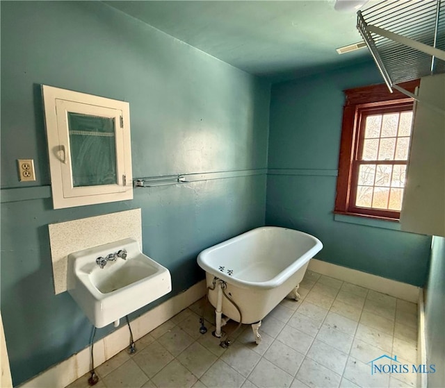 full bathroom with a sink, a freestanding bath, visible vents, and baseboards