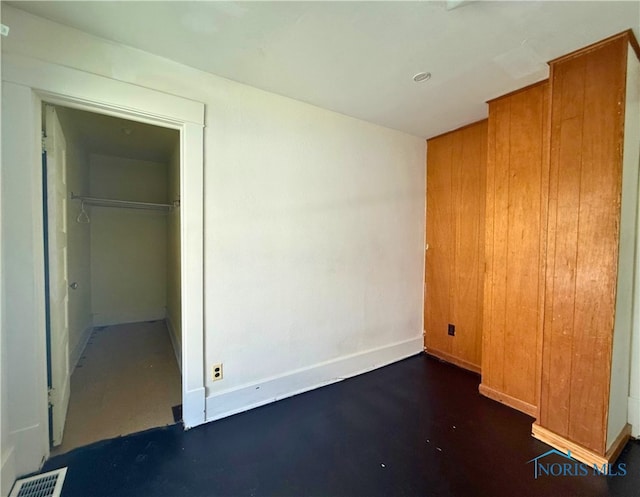 unfurnished bedroom with concrete floors, a closet, visible vents, and baseboards