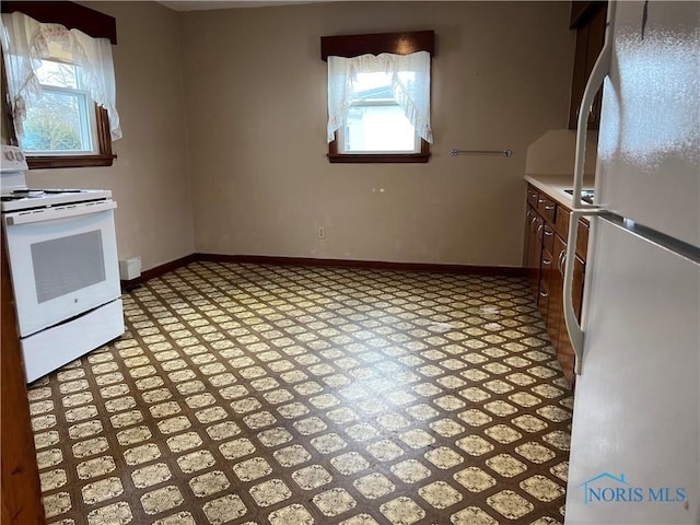 kitchen with white appliances, baseboards, and light countertops