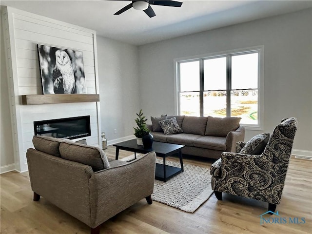 living area featuring visible vents, baseboards, wood finished floors, and a fireplace