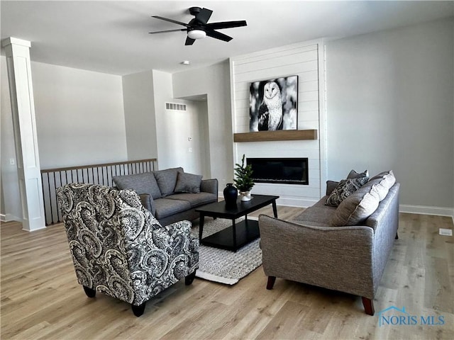 living area with visible vents, wood finished floors, and a fireplace