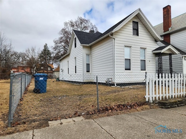 view of side of property featuring fence and roof with shingles