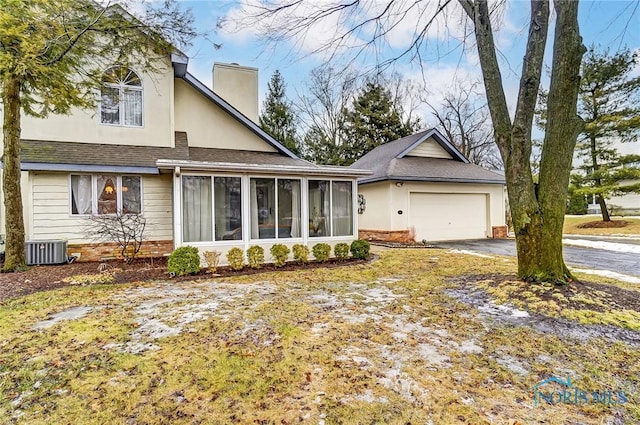 view of front of house featuring a chimney, concrete driveway, a sunroom, a garage, and cooling unit