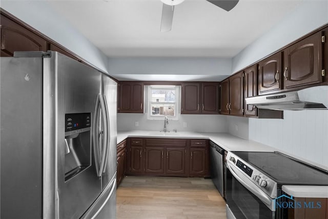 kitchen with light countertops, appliances with stainless steel finishes, light wood-style floors, dark brown cabinetry, and under cabinet range hood