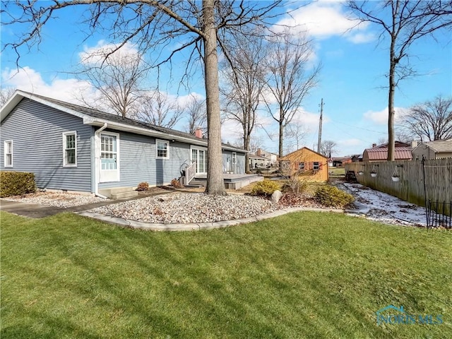 rear view of property with entry steps, fence, a chimney, and a lawn