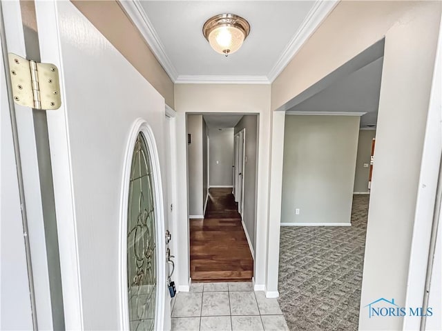 foyer with baseboards, ornamental molding, light colored carpet, and light tile patterned flooring