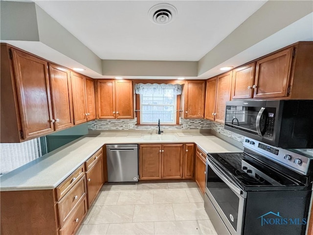 kitchen featuring appliances with stainless steel finishes, light countertops, a sink, and visible vents