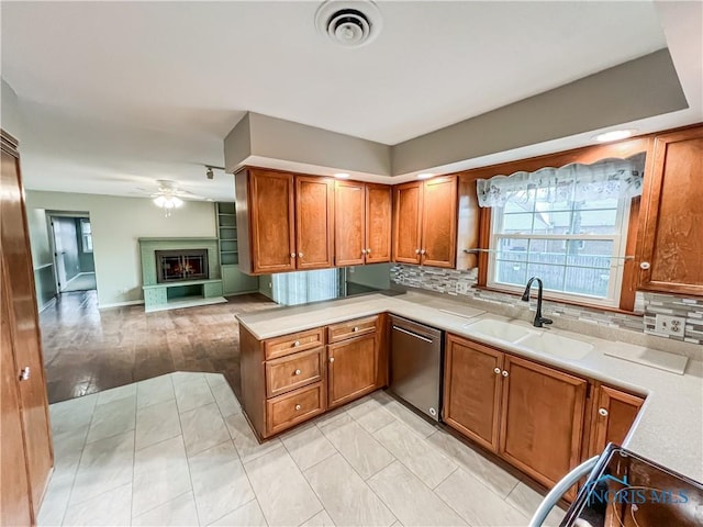 kitchen featuring a sink, open floor plan, light countertops, dishwasher, and a glass covered fireplace