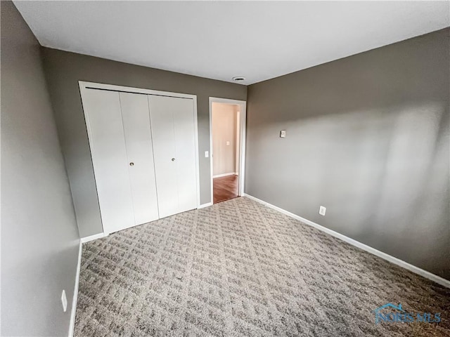 unfurnished bedroom with carpet, baseboards, and a closet