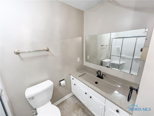 full bathroom featuring baseboards, a shower with shower door, vanity, and toilet