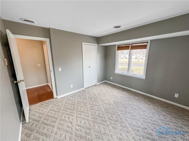 unfurnished bedroom featuring carpet, visible vents, and baseboards