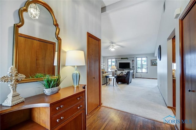 hallway with light wood-type flooring, baseboards, a notable chandelier, and light colored carpet