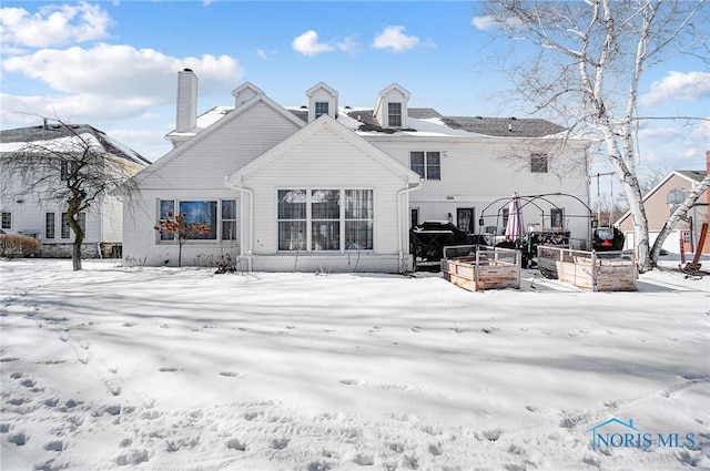 snow covered house featuring a vegetable garden