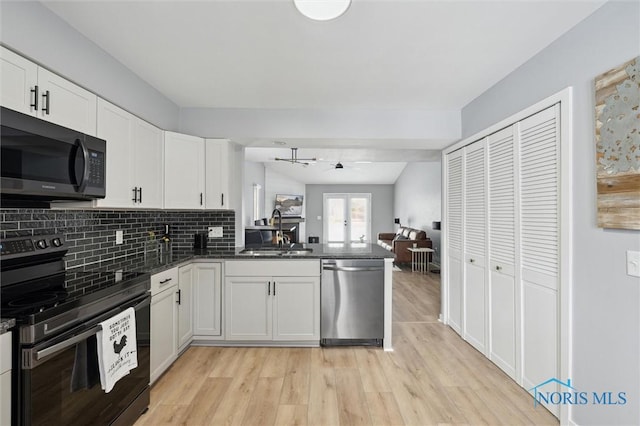 kitchen featuring black range with electric stovetop, a sink, white cabinetry, open floor plan, and stainless steel dishwasher