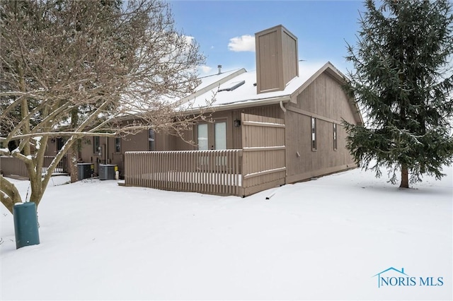 snow covered house featuring central AC