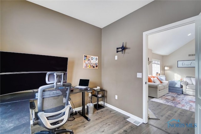 office space with lofted ceiling, visible vents, baseboards, and wood finished floors