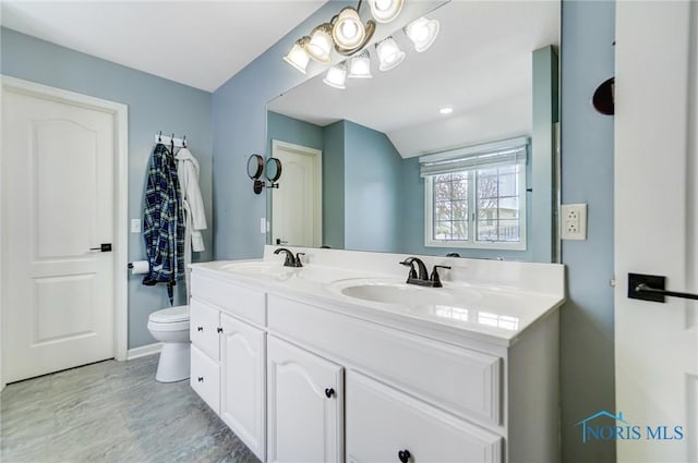 full bath with double vanity, toilet, and a sink