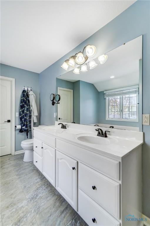 bathroom with double vanity, a sink, and toilet