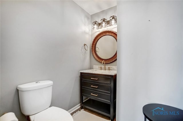 bathroom featuring toilet, baseboards, and vanity