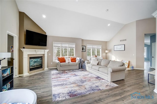 living room featuring high vaulted ceiling, a premium fireplace, visible vents, and wood finished floors