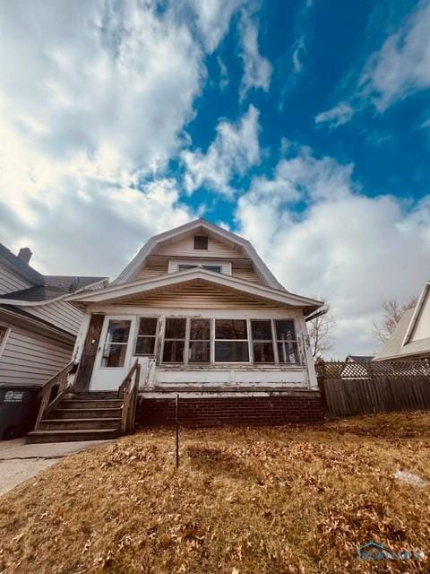 back of property featuring entry steps, a sunroom, fence, and a gambrel roof