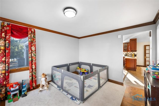 bedroom with ornamental molding, light wood-style floors, and baseboards