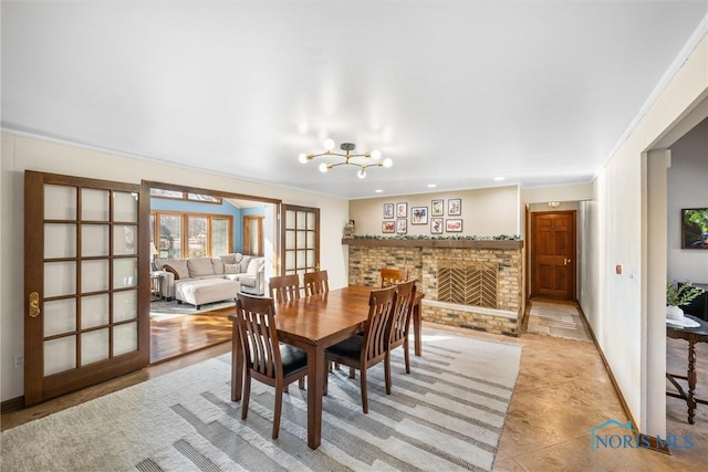 dining area featuring ornamental molding, an inviting chandelier, french doors, a brick fireplace, and recessed lighting