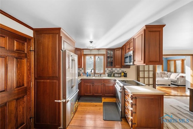 kitchen with decorative backsplash, light wood-style flooring, appliances with stainless steel finishes, light countertops, and a sink