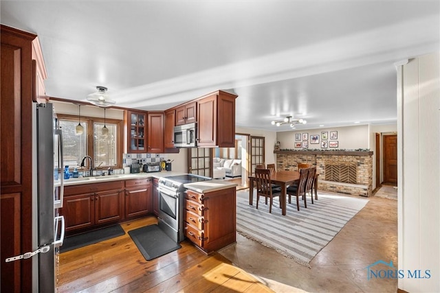 kitchen with light wood finished floors, light countertops, backsplash, appliances with stainless steel finishes, and a sink