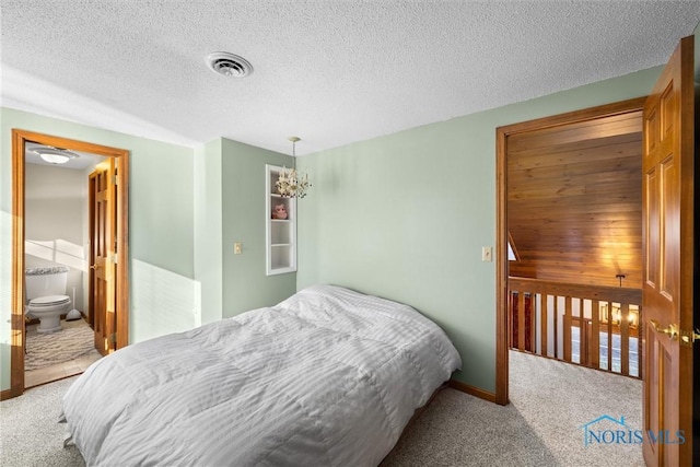 carpeted bedroom with a chandelier, visible vents, connected bathroom, and a textured ceiling