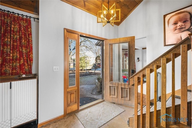 tiled entrance foyer with baseboards, high vaulted ceiling, stairway, and an inviting chandelier