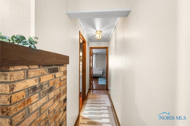 corridor with baseboards, light carpet, and brick wall