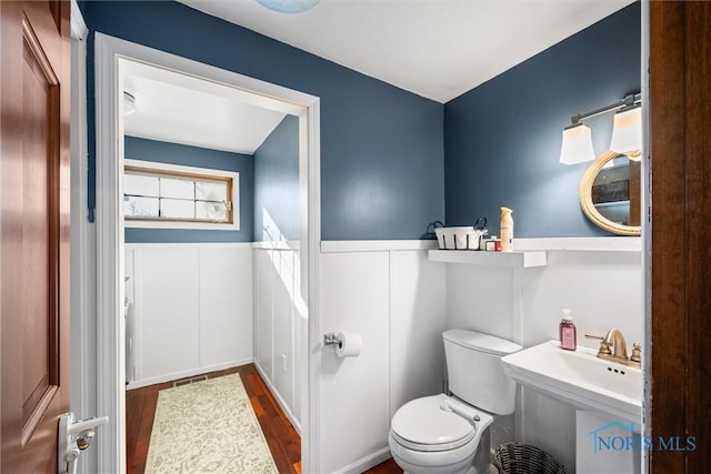 bathroom featuring toilet, wood finished floors, and wainscoting